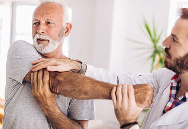 Elderly man getting shoulder adjustment by chiropractor