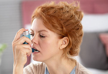 Woman using inhaler for asthma relief
