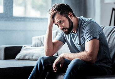 Man sitting on couch dealing with stress at home